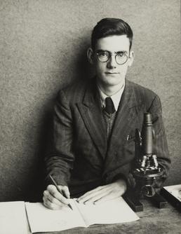 Stanley Moulden, sitting at desk with microscope and…